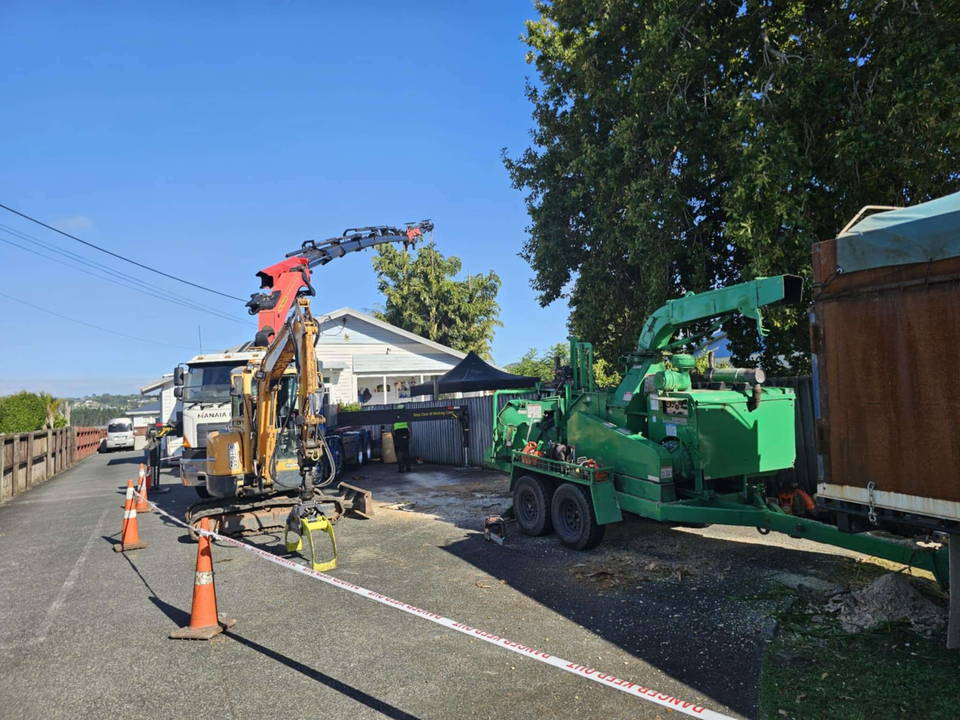Glenn Taylor crew set up on a coned-off Whangarei street with a hiab truck, a mini excavator with a grab and a green wood chipper